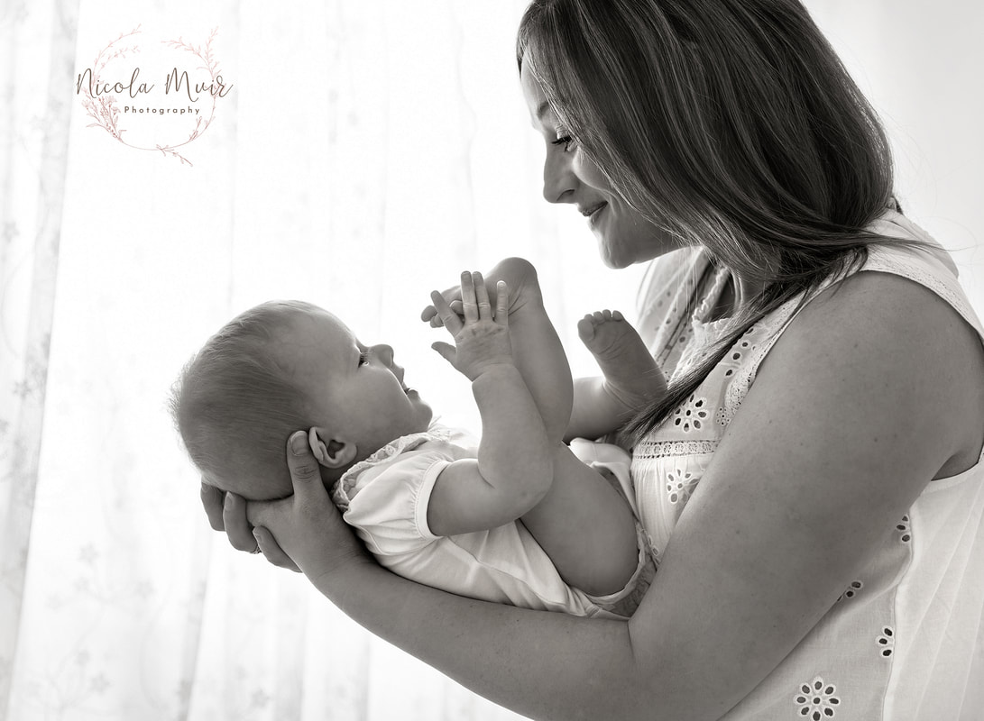 nicola muir photography portrait session baby girl 5 months old in mums ages holding feet monochrome